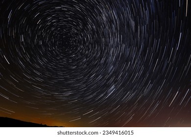 Circular star trails in the sky with a tint of city light from far away on the horizone