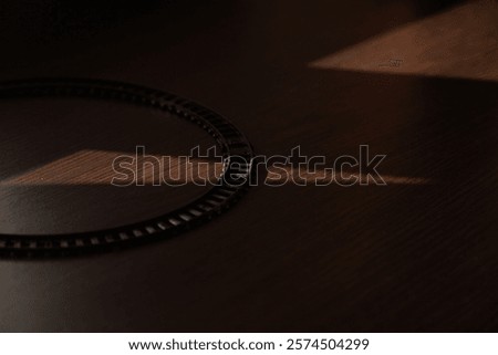 Circular train track on a dark wooden surface, illuminated by a single shaft of sunlight.