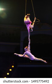 Circus artists. Aerial gymnasts on the trapeze. High altitude flight