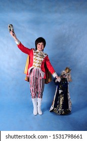 A circus dog dressed as a king with a crown in the Studio on a blue background on October 3, 2014. The trainer in a beautiful suit in the Studio with a smartly dressed dog