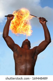 Circus fire-eater blowing a large flame from his mouth