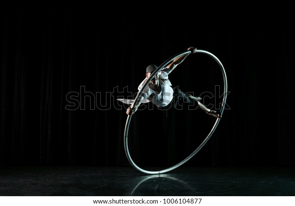  Circus performer artist in a Cyr Wheel\
(Roy Cyr) in theatre at a black\
background