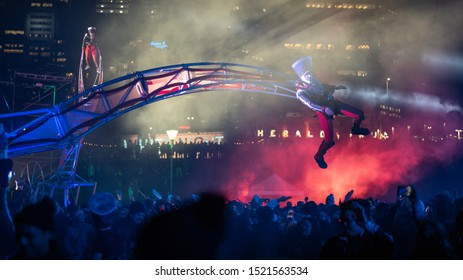 Circus Performers Dressed As Toy Soldiers Fly Overhead Of A Crowd, Suspended By A Mechanical Crane. Free Outdoor Event. White Night Festival, Melbourne, 2019.