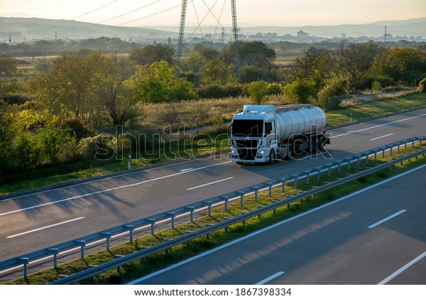 Cistern on the highway through\
countryside.\
White Cistern on the highway. White Cistern driving\
on the asphalt road in rural landscape at\
sunset.