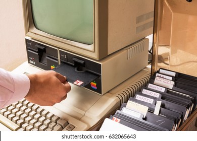 Cisternino, Italy - January 4, 2016: Aged Apple computer and hand insert floppy inside