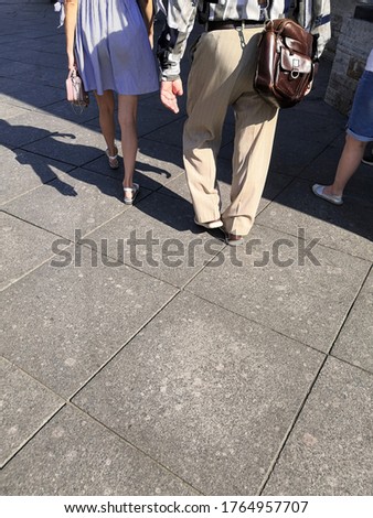 Citizens walking at street sidewalk on sunny summer day