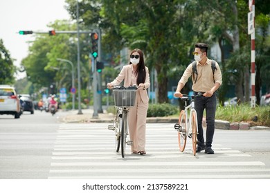 Citizens wearing sunglasses and medical masks when crossing road with bicycles
