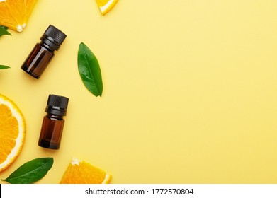 Citrus Essential Oil On A Bright Yellow Background Top View. Slices Of Summer Orange Fruits With Leaves With Glass Jars Flat Lay. Aromatherapy, Natural Alternative Medicine, With Copy Space