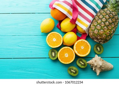 Citrus fresh food. Summer holidays. Orange, kiwi, pineapple, lemon and sea shell on blue wooden background. Top view and copy space. Mock up