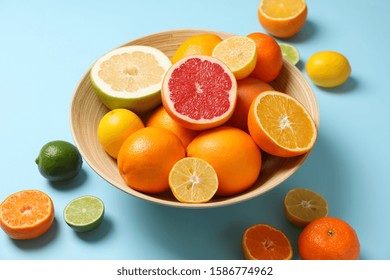 Citrus Fruits And Bowl On Light Blue Background, Close Up