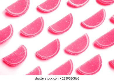 감귤류 젤리를 설탕으로 썰어라. 붉은 보라색 분홍색의 마멀레이드 조각들이 배경에 분리되었다. 반복 패턴, 위쪽 뷰, 플랫 레이입니다. 2023년도의 추세 색상 스톡 사진