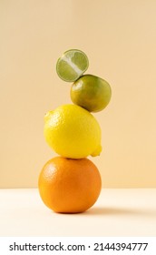 Citrus pyramid: orange, lime, tangerine and lemon balance on a yellow background. Balancing citrus fruits on the table, copy space. Equilibrium floating food balance.