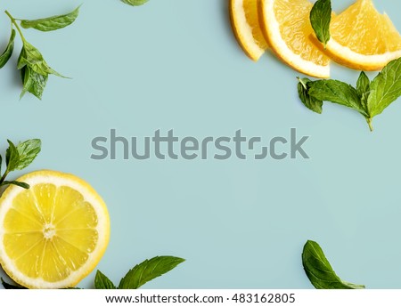 Citrus slices and mint herbs frame on retro mint pastel background with copyspace from above. Top view of lemon and orange refreshment. Summer fruit smoothie minimal banner design.