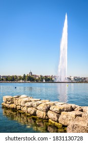 The city and bay of Geneva, Switzerland, seen from a stone jetty by a sunny summer morning with the cathedral and the Jet d'Eau, the 140 meter-high water jet fountain on the Lake Geneva.