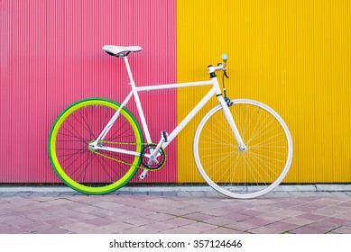 City bicycle fixed gear on yellow and red wall. Cycling or commuting in city urban environment, ecological transportation concept.