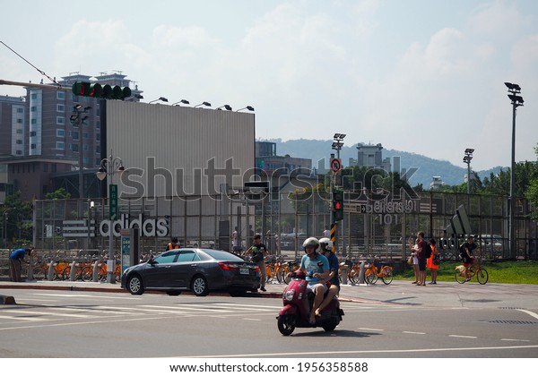 City bike\
parking for hire and rare tourists. Sports ground behind the fence.\
A sparsely populated intersection on the streets of the city on a\
hot sunny day. Taiwan. Taipei 2016.\
07.30