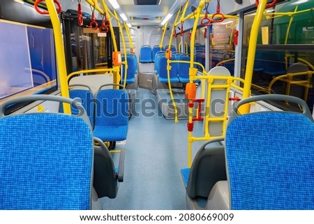 City bus. Ground transportation in city. Passenger seats in tram. City bus interior. Municipal transport with validators. Passenger transport. Blue armchairs in modern illuminated autobus