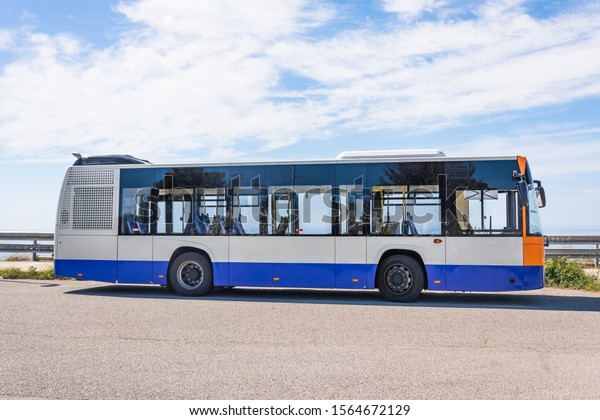 City bus on the side of the road stop, side\
view on sky background
