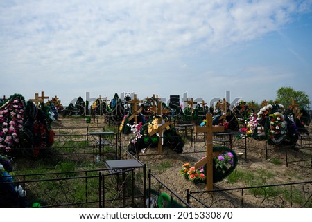 City cemetery with wooden crosses over the graves. Recent burials of people in the cemetery. Commemorative crosses with wreaths.