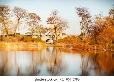 In The City Of Chicago In Fall Near Lincoln Park With A Bridge, Lake And Orange Colored Trees With Gorgeous Reflections.