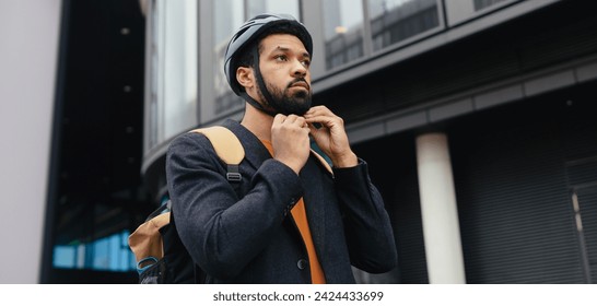 City commuter, businessman traveling from work to home on bike, fastening helmet for safety. City lifestyle of single man. - Powered by Shutterstock