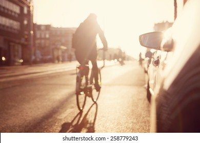 City Commuters. High Key Blurred Image Of People Riding A Bike In The Street. Unrecognizable Faces.