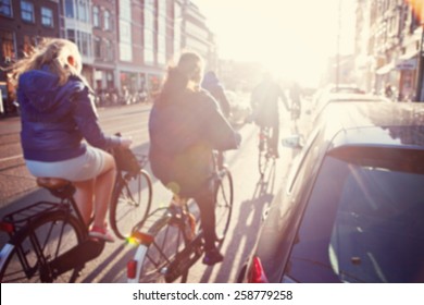 City Commuters. High Key Blurred Image Of People Riding A Bike In The Street. Unrecognizable Faces.