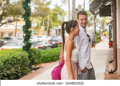 City couple happy in love young man and woman walking on street shopping looking at shop stores talking together, Naples, Florida, USA travel vacation.