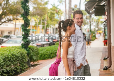 City couple happy in love young man and woman walking on street shopping looking at shop stores talking together, Naples, Florida, USA travel vacation.