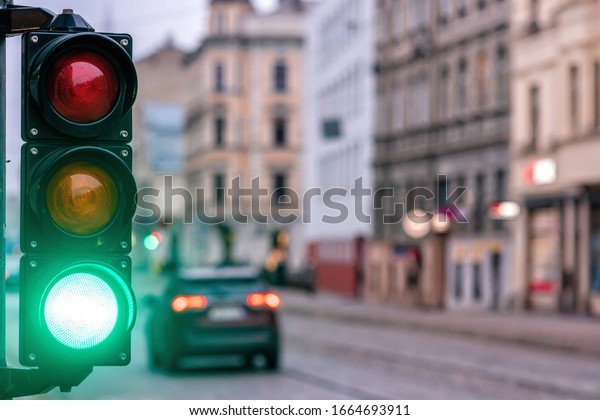 A city crossing with a semaphore. Green light in\
semaphore - image