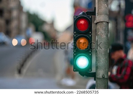 a city crossing with a semaphore on blurred background with cars in the evening streets, green light
