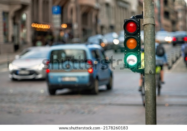 a city crossing with a\
semaphore on blurred background with cars in the evening streets,\
green light
