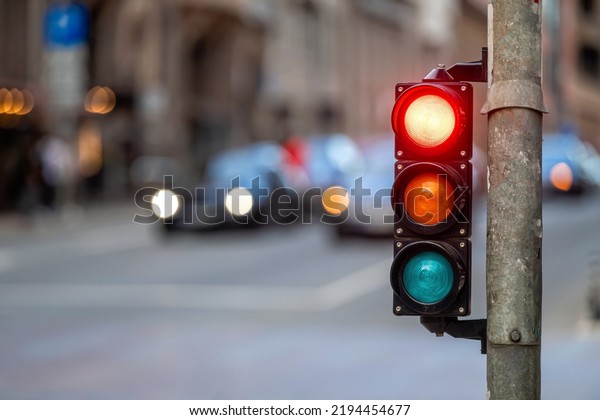 city crossing with a semaphore\
on blurred background with cars in the evening streets, red\
light