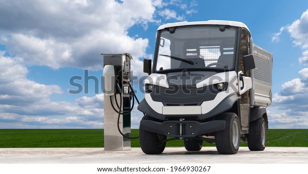 City\
delivery electric truck with charging station on a background of\
green field and blue sky. Clean mobility\
concept