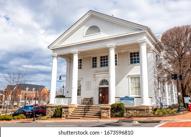 City of Fairfax, USA - March 10, 2020: Old town hall colonial architecture with sign for Huddleson Memorial public library, community events in downtown at University drive in Fairfax county, Virginia