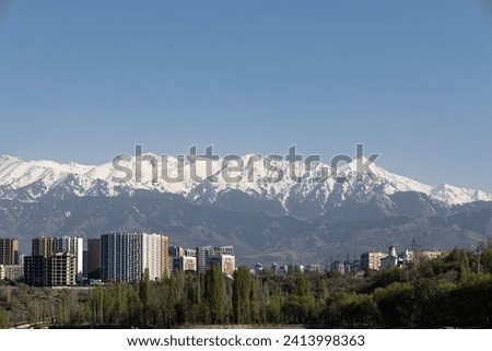 City at the foot of the mountains with snow-capped peaks. multi-storey residential buildings against the backdrop of the Tien Shan mountain range. Almaty, Kazakhstan at spring time. Central Asia urban