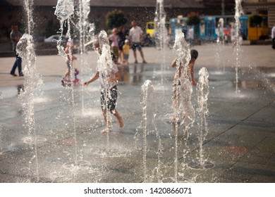 City fountain in the summer heat. Children running and playing between water flows - Shutterstock ID 1420866071