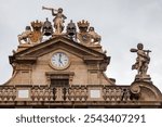 The City Hall in Pamplona showcases intricate architecture, adorned with flags and sculptures under a cloudy sky.