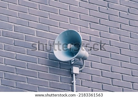 City hazard warning system. Loud speaker on brick wall. Megaphone hanging on building. Providing security in town, notification of emergencies.