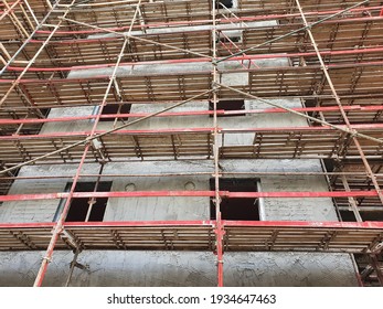 City housing renovation project. Construction site. Red scaffoldings. Wooden platforms. Gray wall. Closeup. National outline plan. NOP - TAMA 38. Tel Aviv, Israel. - Shutterstock ID 1934647463