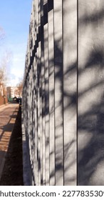 City labyrinth. Boundary between public and private space. Metal fence of silver stripes along city sidewalk on sunny day. Vertical photo. Urban geometric patterns. Selective focus - Shutterstock ID 2277835309