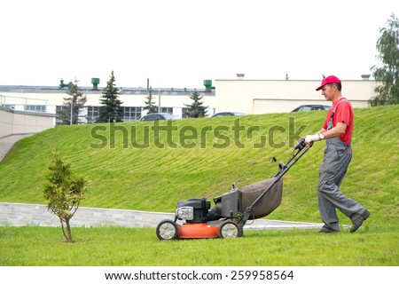 City landscaper cutting grass with lawn mower