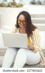 City Life Portrait Of Beautiful And Smiling Stylish Plus Size Business Woman 30-35 Years Old In Yellow Fashion Clothes And Sunglasses, Working Remotely On A Laptop On Vacation