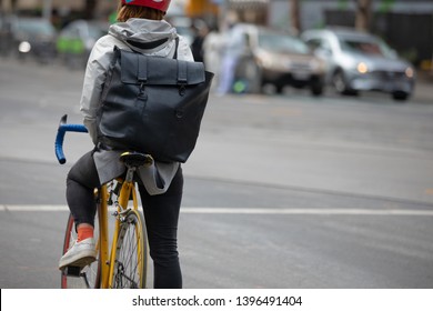City lifestyle exercise and go to work by bicycle. The rider wearing fashion outfit with the bag pack and jacket in the
				winter time.Back view.