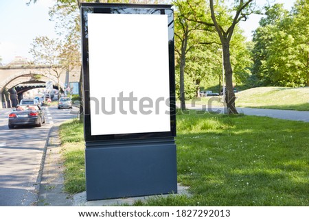City Light Poster Mock-Up Template on street next to a green park in the city