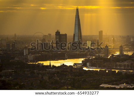 the city of london skyline at sunset, zoomed in from a high vantage point far away. amazing sunrays are captured during this scene