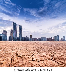 A city looks over a cracked earth landscape - Shutterstock ID 713784526