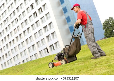 City man landscaper worker cutting grass with lawn mower machine