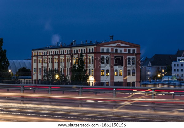 CITY AT NIGHT - An industrial building with an\
expressway in the\
background