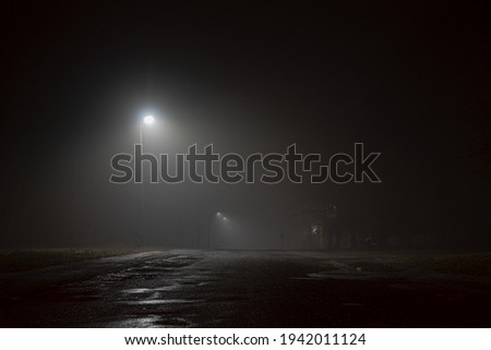 City at night with lanterns' light. Road in the fog.